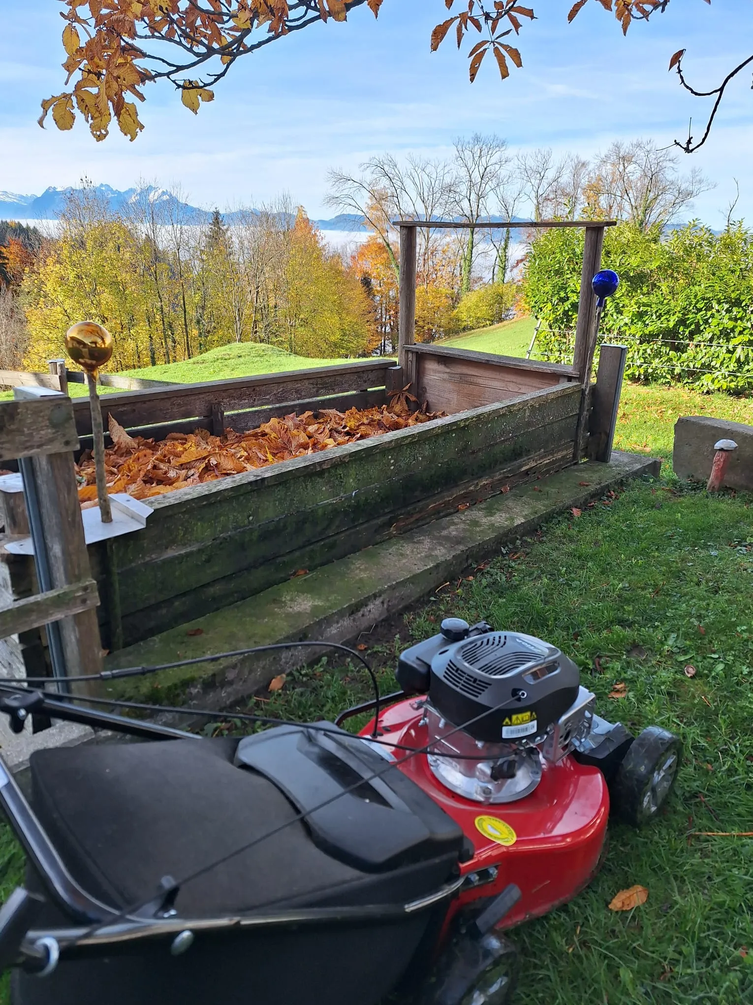 Rasenmäher vor dem Kompost mit Blick ins herbstliche Tal
